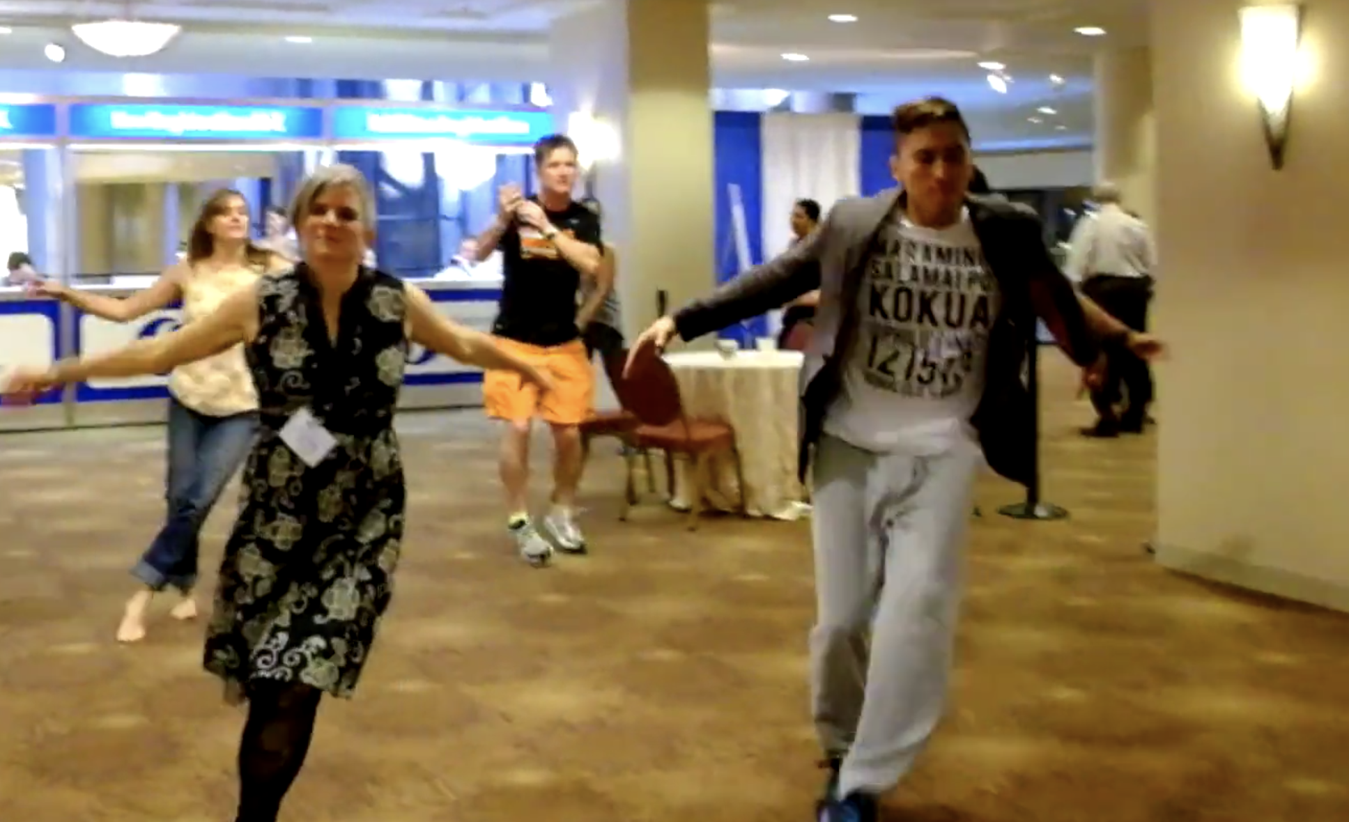 One white woman and Brown man dance in a lobby